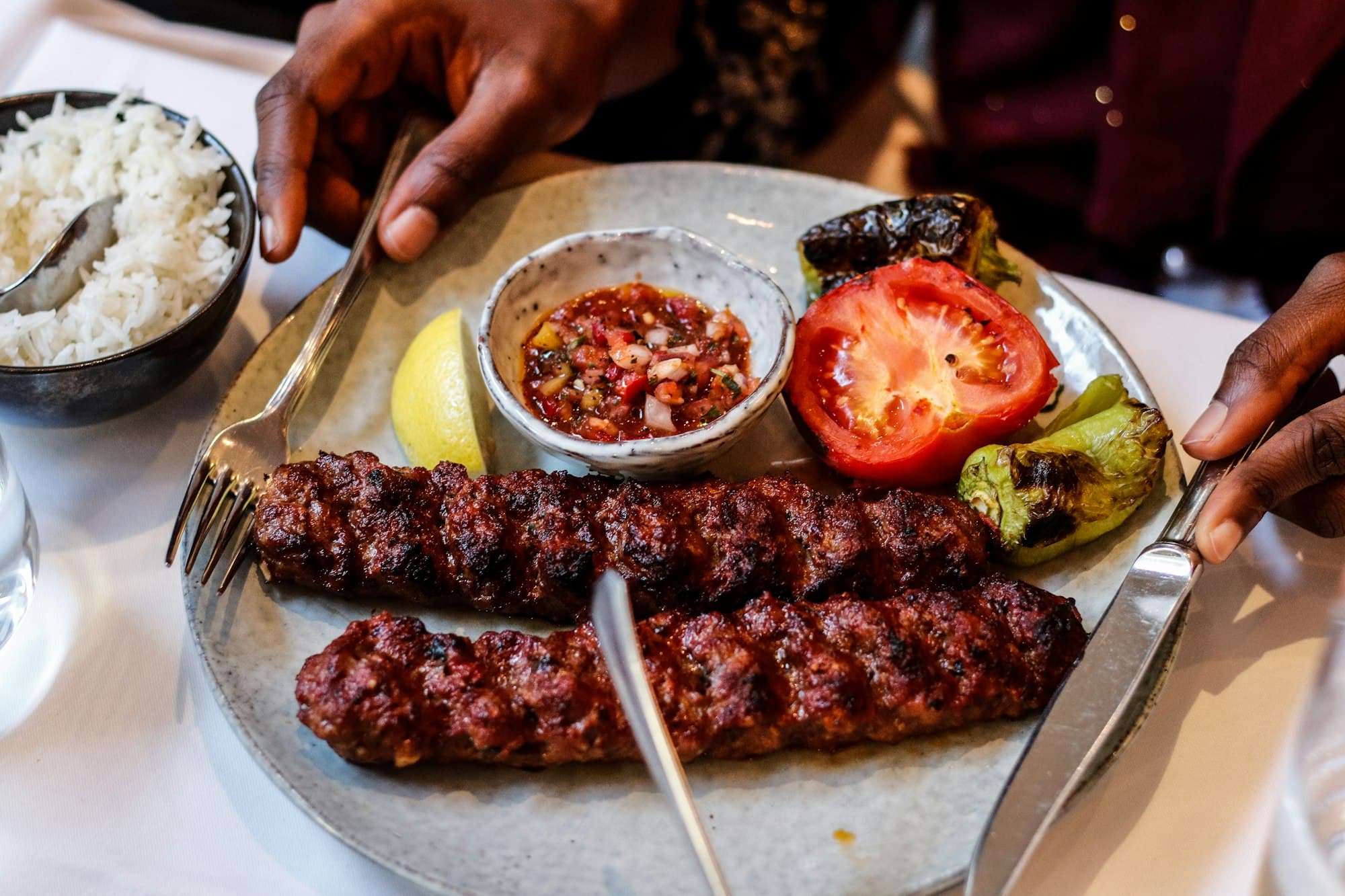 A kebab plate with rice, lemon and salsa