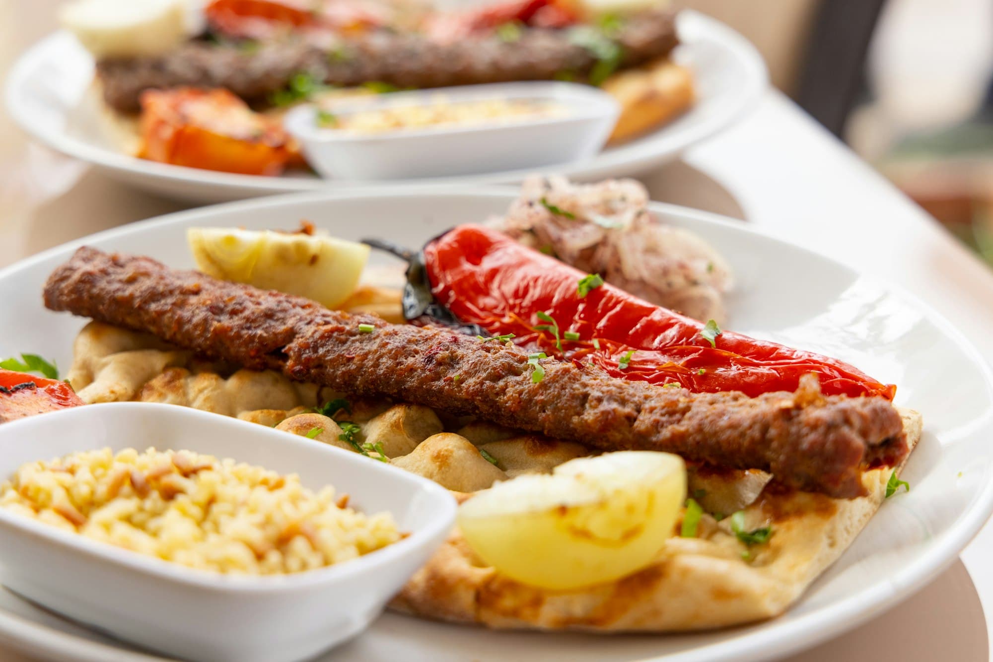 Kofta kebab on flatbread with rice pilaf, table set for two