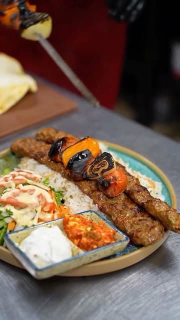 A kebab platter with rice, salad and dips